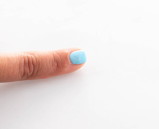 Finger mit hellblauem Nagellack von Namaki, abziehbar, Detailaufnahme der Politur auf dem Fingernagel