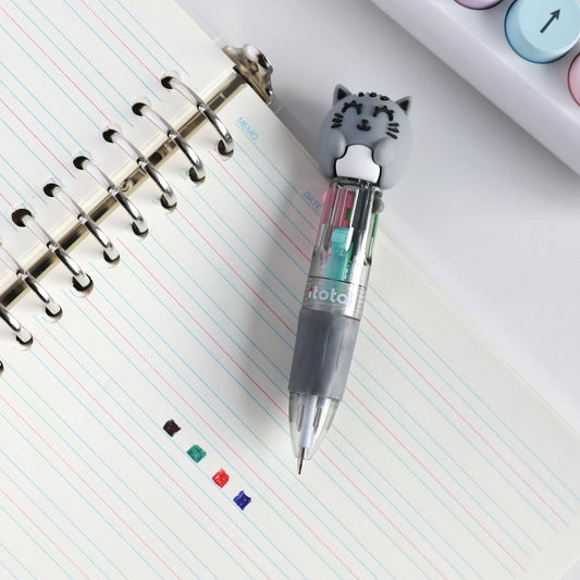 Mini-Stift mit Kopf als graue Katze auf einem Spiralblock, daneben Punkte in den vier Tintenfarben