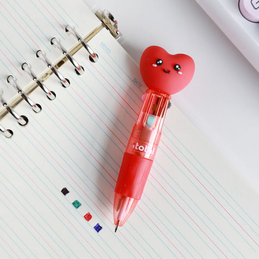 Mini-Stift mit Kopf als Herz auf einem Spiralblock, daneben Punkte in den vier Tintenfarben