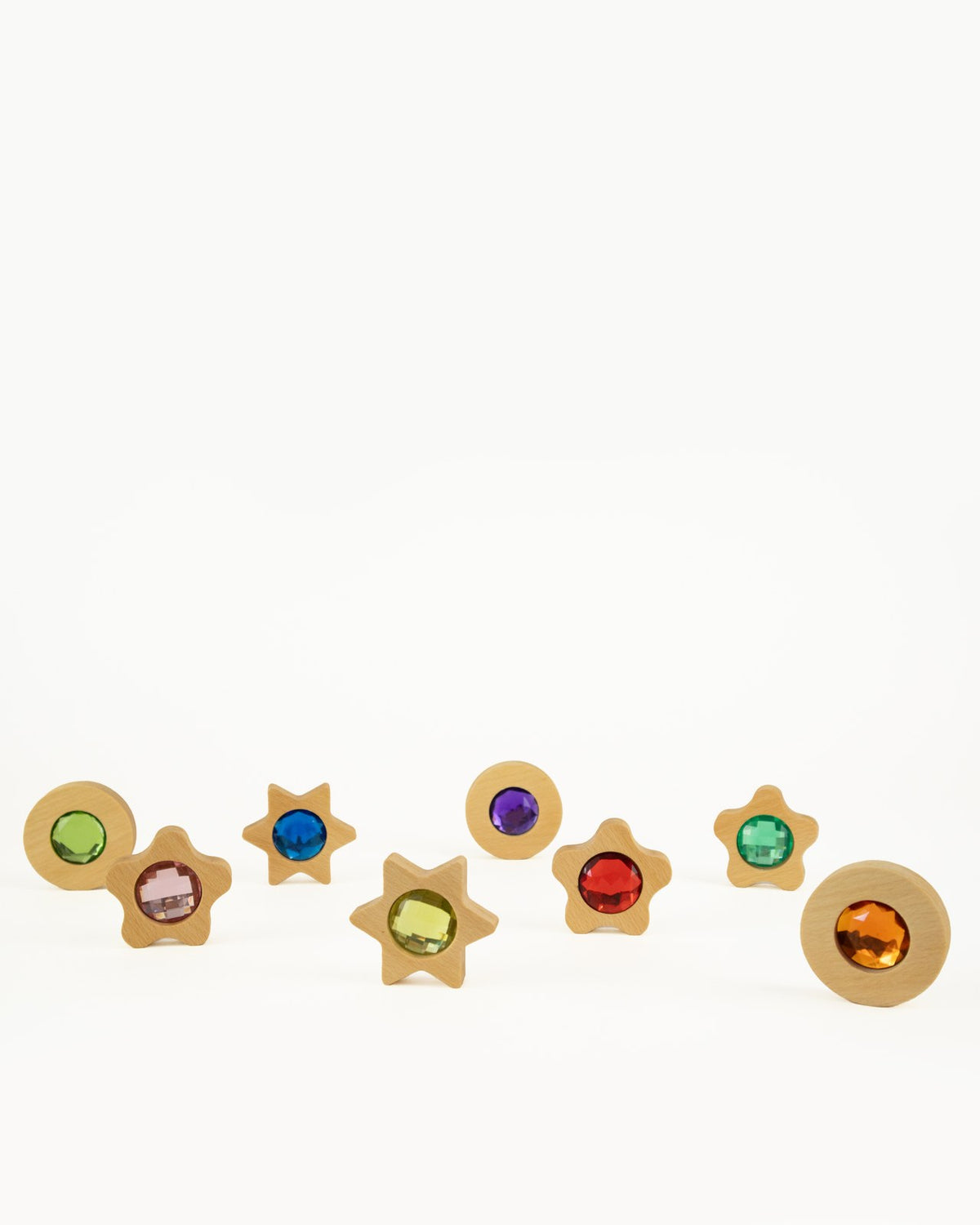 Alle acht Spieltaler aus Holz in Stern- und Kreisform mit verschiedenfarbigen Glitzersteinen angeordnet nebeneinander