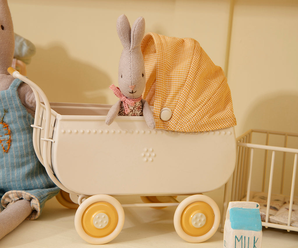 Kleiner Stoffhase sitzt im cremefarbenen Maileg Kinderwagen mit gelb kariertem Verdeck, Nahaufnahme
