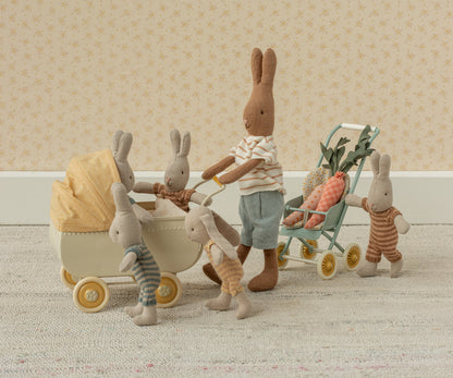 Hasenfamilie aus Stoff schiebt den Maileg Kinderwagen Mikro mit gelbem Verdeck, daneben ein grüner Buggy