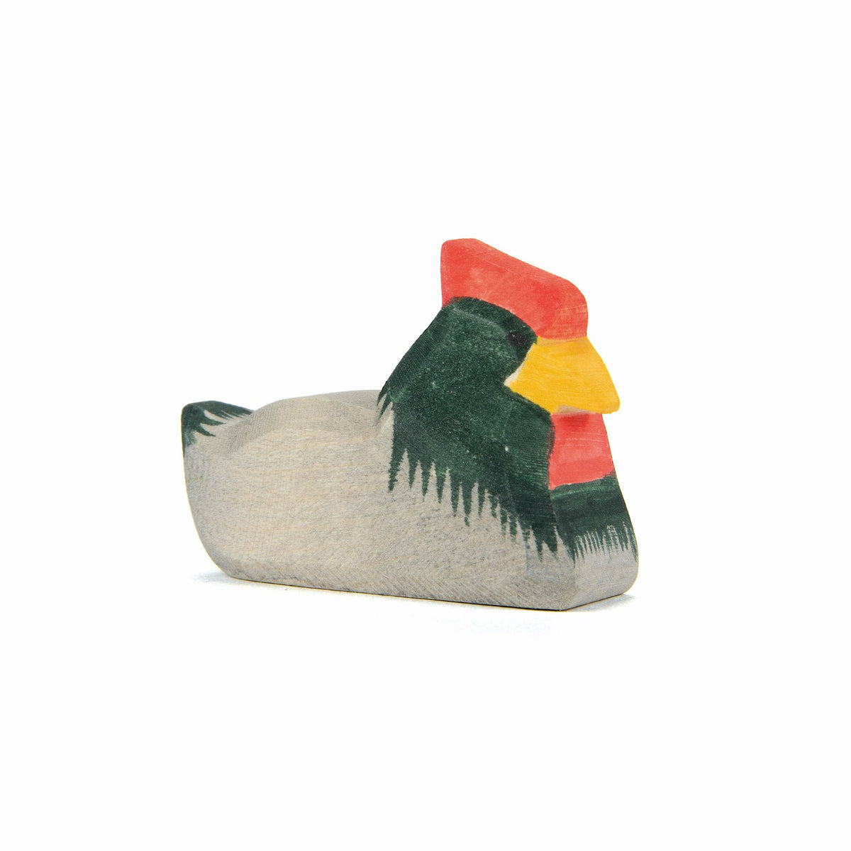 Ostheimer Holzfigur Huhn liegend mit beige Körper, dunkelgrünen Flügeln, rotem Kamm und gelbem Schnabel