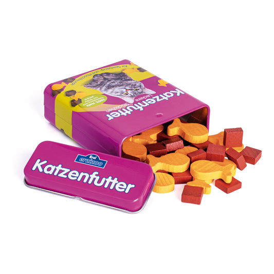 Erzi Katzenfutter in der Dose: violette Dose, daneben ausgeschüttete bunte Holz-Futterstücke