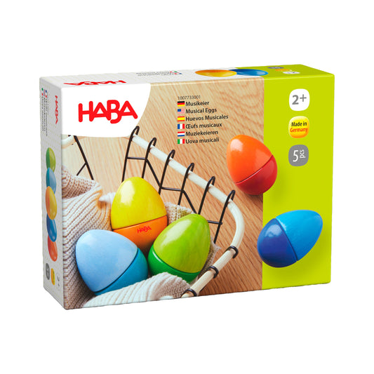 Haba Musikeier Packshot mit fünf bunten Holzrasseln und schwarzen Griffen auf Holzuntergrund