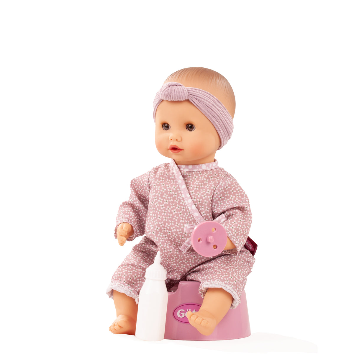 Götz Sleepy Aquini Girl Soft Mood sitzt auf dem rosa Töpfchen, trägt altrosa Overall und lila Stirnband