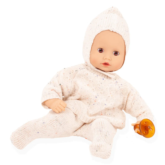 Götz Muffin Baby Alles Strick im beigen Strickanzug mit Mütze, sitzend, daneben ein orangefarbener Schnuller