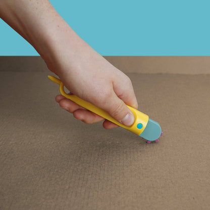 Hand rollt den gelben Makedo Fold-Roller über Karton und zieht damit eine Falzlinie