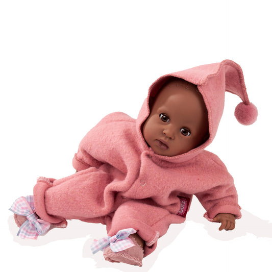 Puppe in rosa Götz Babyanzug mit Zipfelmütze und Pom-Pom, trägt lila-weiße Stoffschuhe, sitzt in Kriechposition