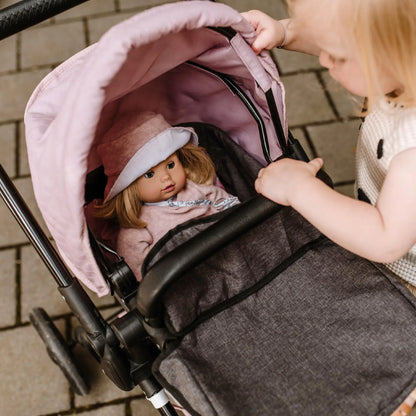 Kind öffnet das rosa Verdeck des Götz Puppenwagens 2 in 1 Soft Mood und schaut auf die darin liegende Puppe mit braunem Haar