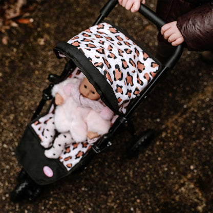 Kind schiebt den Götz 3-Rad Puppen-Buggy mit Leoparden-Muster, darin eine Puppe in weißem Outfit