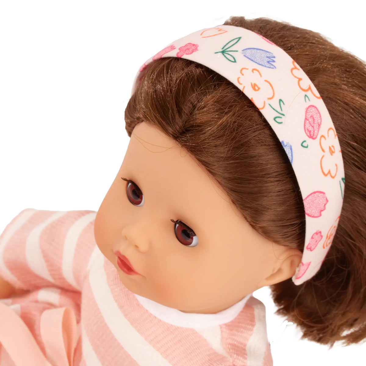 Götz Haarreif mit Blumenmuster auf Puppe mit braunem Haar, rosa-weißem Streifenshirt und roten Lippen getragen