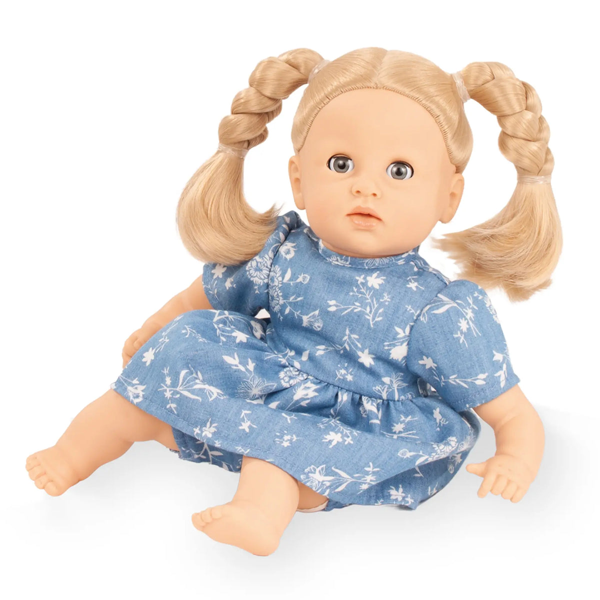 Götz Puppenkleid Denim Flowers angezogen auf einer Babypuppe mit blonden geflochtenen Zöpfen und blauen Augen
