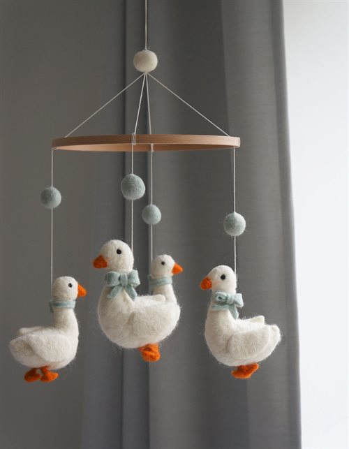 Filz-Mobile mit weißen Gänsen und graublauen Filzkugeln an einem Holzring