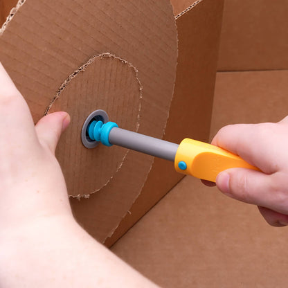 Hand führt Makedo Scru+ Schraube mit grauem Schaft und orangegelbem Griff in Kartenloch