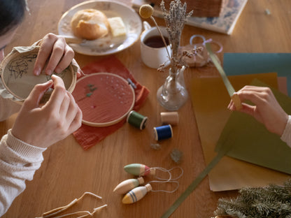 Kind arrangiert Grapat Winter Sparkles Ornaments auf Holztisch mit Dekoration und Bastelmaterial