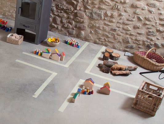 Grapat Houses and Nins auf Spielfläche arrangiert mit Holzhäusern, bunten Holzfiguren, Naturmaterialien und Körben in Szene