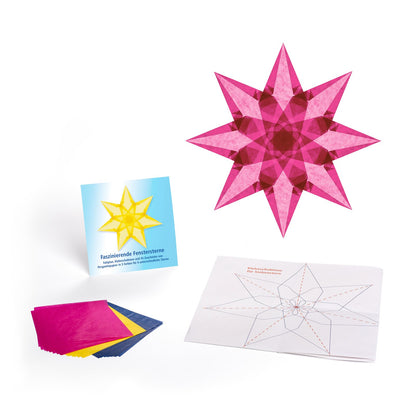 Ausgepacktes Set Faszinierende Fenstersterne: Kartontasche, Pergaminpapier in Magenta, Tiefblau und Hellgelb, Faltplan und ein fertiger magentafarbener Stern