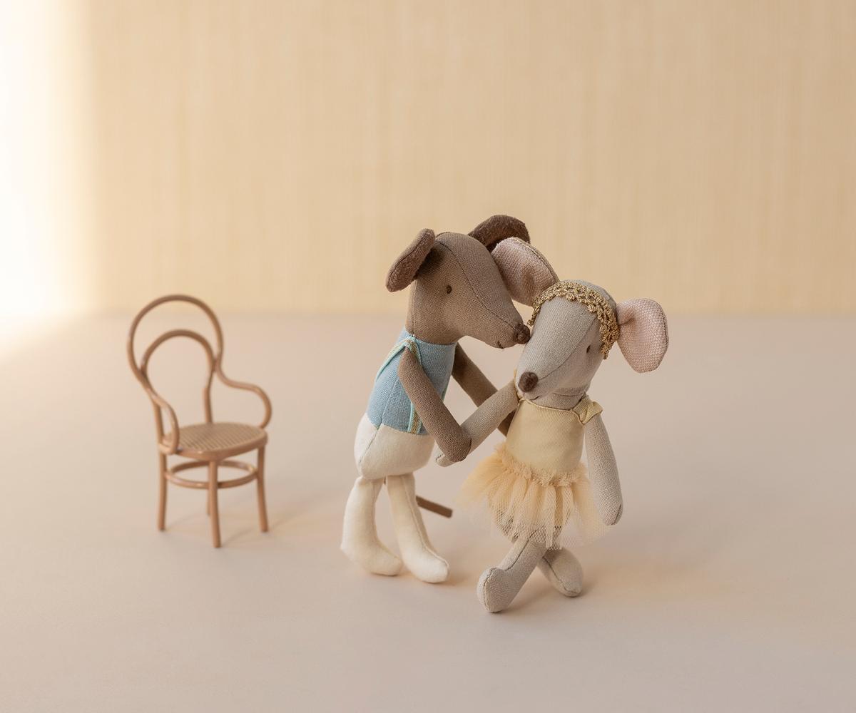 Maileg Balletttänzerin Maus im Tutu tanzt mit einer dunkleren Maus im blauen Oberteil neben einem Stuhl