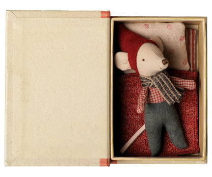 Aufgeklapptes Maileg Buch von oben: die Babymaus mit roter Mütze liegt im Bett unter einer roten Decke