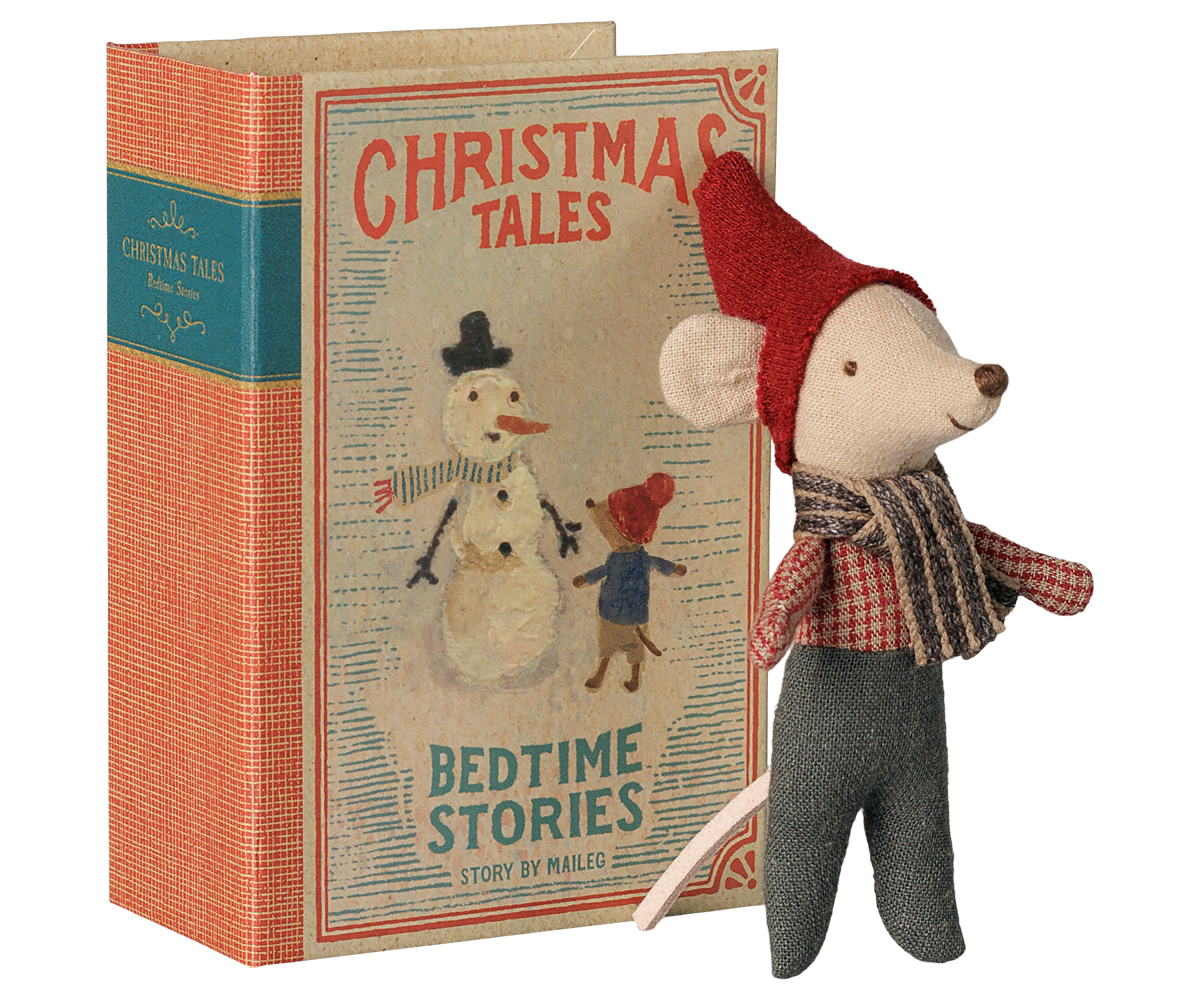 Maileg Weihnachtsmaus Baby mit roter Zipfelmütze und Schal steht vor ihrem Buch mit Aufschrift Christmas Tales