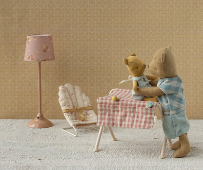 Maileg Babysitter Mikro in Creme steht neben einem Tisch, an dem zwei Teddybären spielen