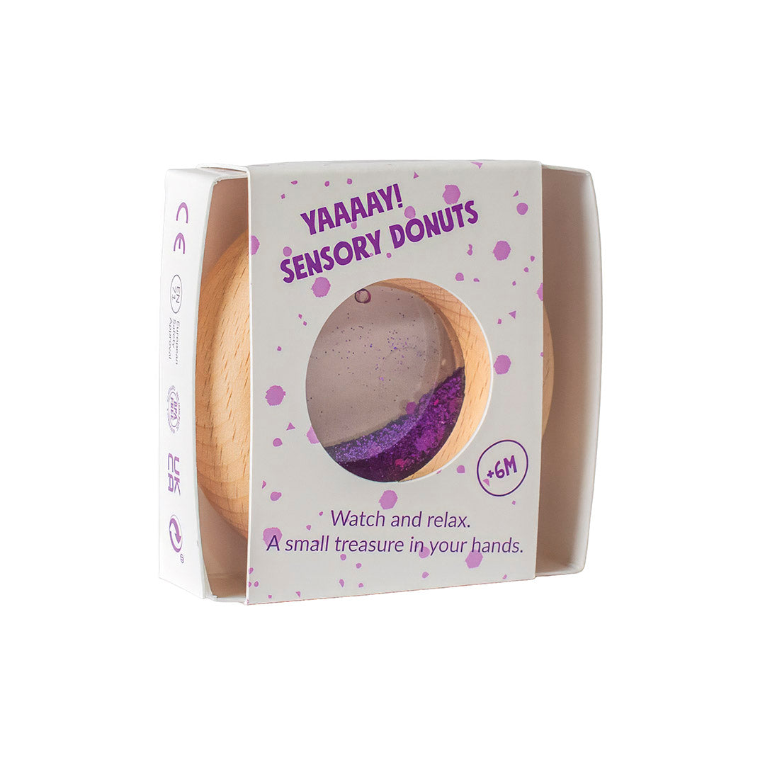 Verpackung des Petit Boum Sensorik-Donuts Lila mit Holzrahmen und Durchsichtsfenster, Text YAAAY Sensory Donuts auf Karton