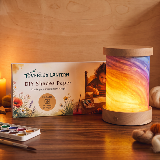Toverlux DIY Shades Paper: Verpackung neben einer leuchtenden Laterne mit selbst bemaltem Schirm in Regenbogenfarben