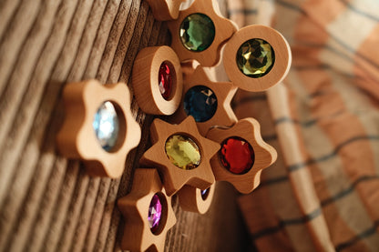 Bauspiel Spieltaler an Holzwand, Sonnenlicht wirft bunte Lichter durch die Funkelsteine