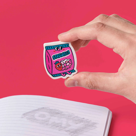 Hand hält den Radierer OMY Eraser Buddies Betty in Form einer rosa Strawbies-Tüte vor rosa Hintergrund