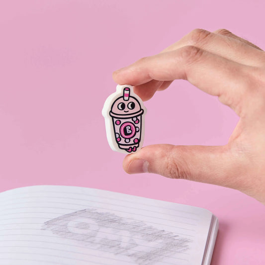OMY Eraser Buddies Bubble-Tea-Radierer rosa-weiß zwischen Daumen und Zeigefinger gehalten vor rosa Hintergrund