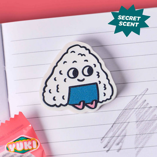 OMY Eraser Buddies Yuki, Onigiri-Radierer mit Gesicht und blauem Nori-Blatt auf liniertem Papier