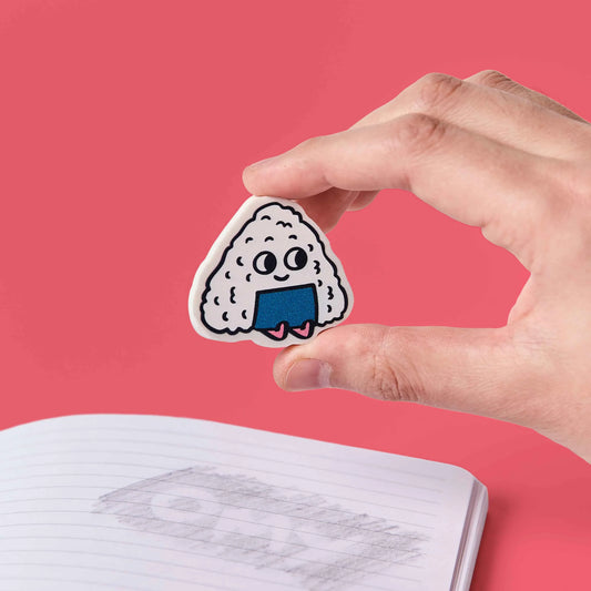Hand hält den Onigiri-Radierer OMY Eraser Buddies Yuki über einem Notizbuch