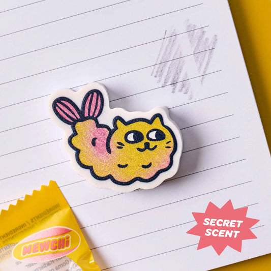 OMY Eraser Buddies Mewchi, gelbe Tempura-Garnele mit Katzengesicht und rosa Schwanz auf liniertem Papier