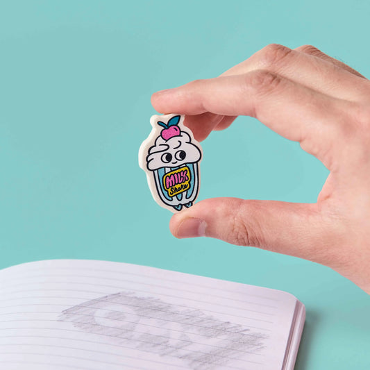Hand hält den Milchshake-Radierer OMY Eraser Buddies Shaky über ein offenes Notizbuch