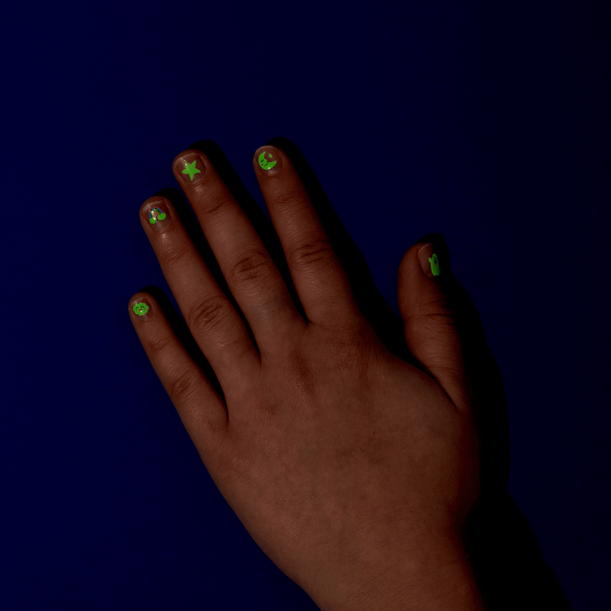 OMY Glow Party Nagelsticker mit neongelben und grünen Sternen auf Fingernägeln, leuchtend vor dunkelblauem Hintergrund