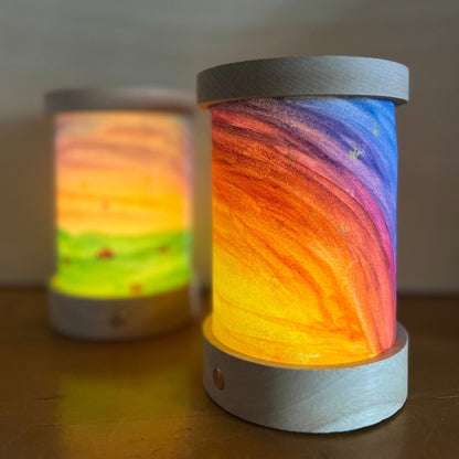 Zwei leuchtende Toverlux Laternen mit selbst bemalten Papierschirmen in Regenbogenfarben, Nahaufnahme
