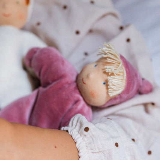 Kind hält die Käthe Kruse Waldorfpuppe LOLO rose im altrosa Anzug mit hellen Ponyfransen im Arm