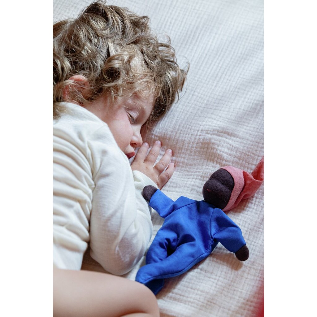 Schlafendes Kleinkind mit Locken liegt neben der Käthe Kruse Waldorfpuppe NINI Sommerwolke im blauen Anzug