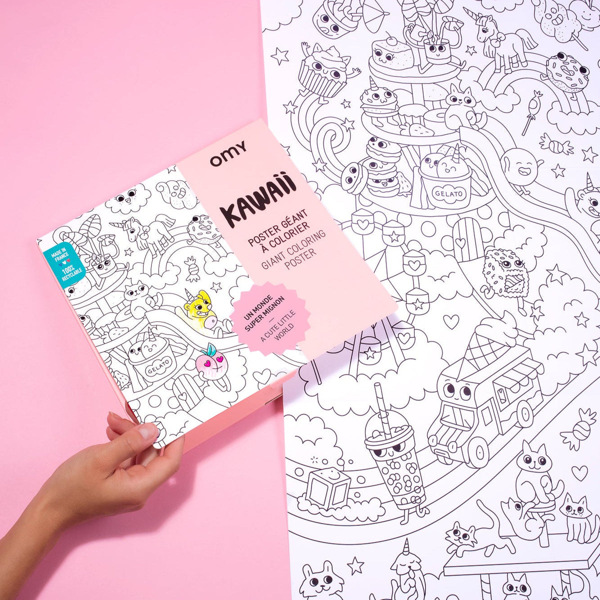 Hand hält OMY Kawaii Riesen-Ausmalposter aufgeklappt mit rosa Verpackung und Ausmalbild mit Kawaii-Motiven