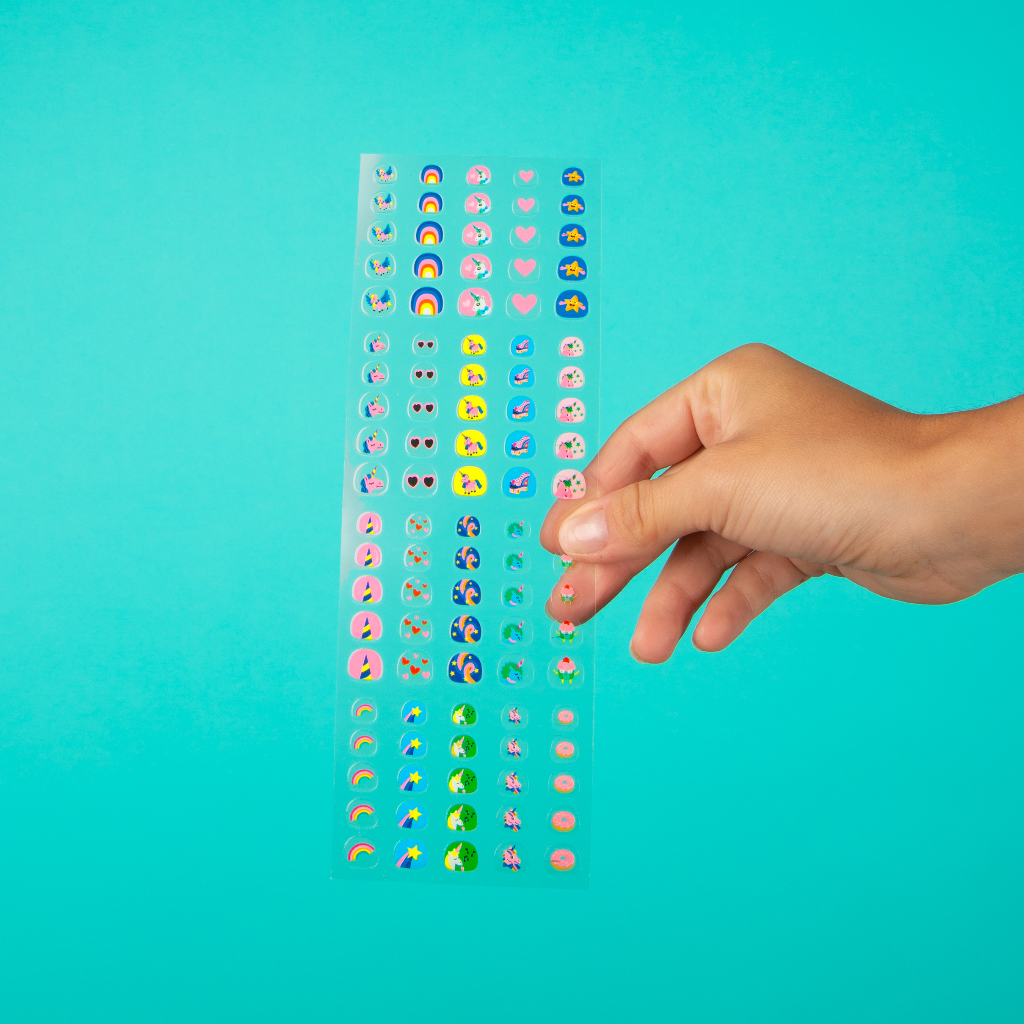 Kinderhand greift nach Stickertafel mit bunten Gesichtern und Motiven, OMY Nagelsticker Lily