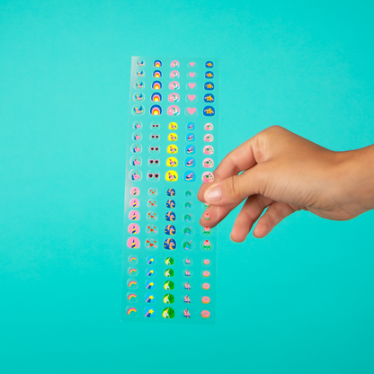 Kinderhand greift nach Stickertafel mit bunten Gesichtern und Motiven, OMY Nagelsticker Lily