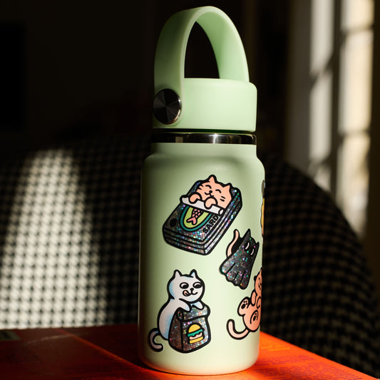 OMY Kitty Sticker auf einer hellgrünen Flasche mit Henkel, bedruckt mit Katzen und bunten Motiven