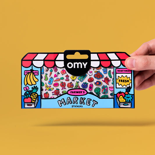 OMY Farmer's Market Sticker-Verpackung in Marktstandform mit bunten Obst- und Gemüsemotiven, Hand hält sie