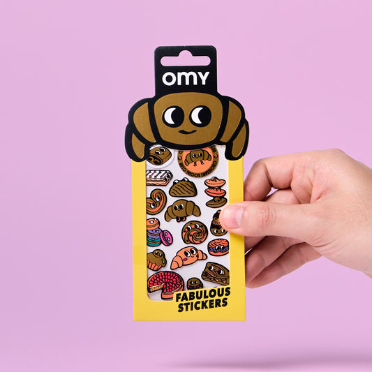 OMY Iconic Croissant Sticker-Packung mit Hunde-Kopf-Design in Hand vor rosa Hintergrund
