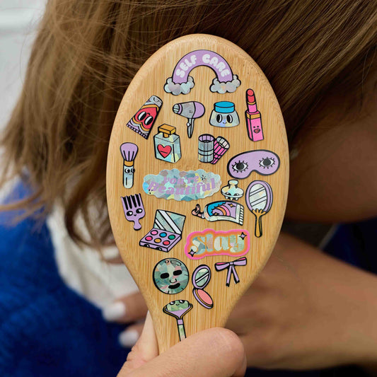 Kind hält OMY Holzspatel mit bunten aufgedruckten Beauty-Sticker-Motiven