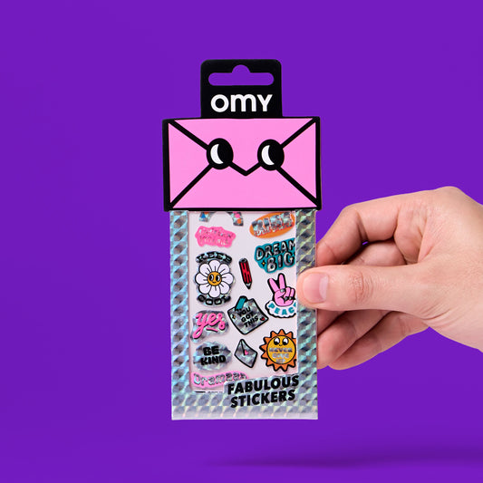 OMY Iconic Messages Sticker, Hand hält Packung mit rosa Briefumschlag-Design vor violettem Hintergrund