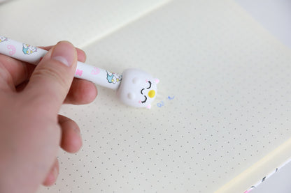 Hand hält den Stift mit Figur Einhorn und radiert damit Schrift auf Punktrasterpapier