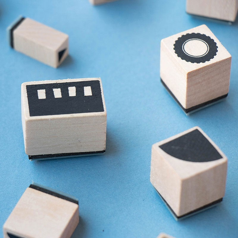 Vier Holzstempel des Londji BAM! Transports Sets auf blauem Grund mit geometrischen Formen