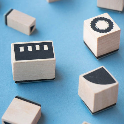 Vier Holzstempel des Londji BAM! Transports Sets auf blauem Grund mit geometrischen Formen